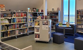 Blick in die Gemeindebücherei Buchdorf Blick auf gut befüllte Bücherregale in der Bücherei in Buchdorf. Rechts im Bild sieht man eine Sitzgruppe.